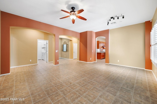 7708 N Siesta Sunset Ln, Prescott Valley, AZ 86315 - unfurnished living room with arched walkways, a ceiling fan, baseboards, and track lighting