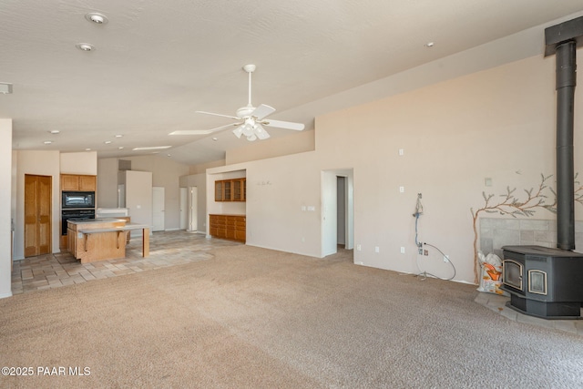 1269 N Oxbow Dr, Dewey-Humboldt, AZ 86327 - unfurnished living room featuring a wood stove, a ceiling fan, vaulted ceiling, and light colored carpet