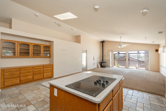 1269 N Oxbow Dr, Dewey-Humboldt, AZ 86327 - kitchen with open floor plan, black electric cooktop, a wood stove, vaulted ceiling, and brown cabinets