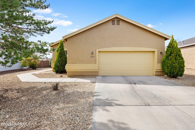 view of front of home featuring a garage, driveway, fence, and stucco siding