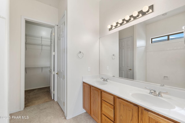 full bath with double vanity, tile patterned flooring, a walk in closet, and a sink