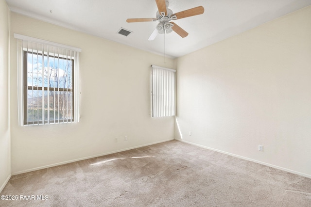 carpeted empty room with baseboards, visible vents, and a ceiling fan