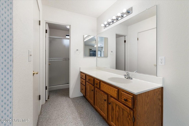 full bathroom featuring a shower with shower door and vanity