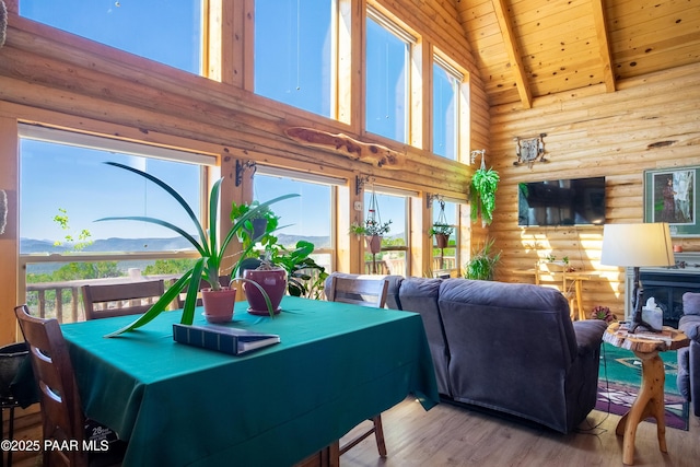 dining space featuring high vaulted ceiling, light hardwood / wood-style floors, a mountain view, wooden ceiling, and beam ceiling