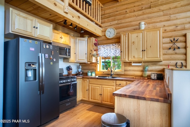 kitchen featuring butcher block countertops, sink, light hardwood / wood-style flooring, appliances with stainless steel finishes, and light brown cabinetry