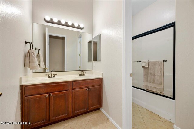 bathroom featuring tile patterned flooring, vanity, and shower / bath combination with glass door