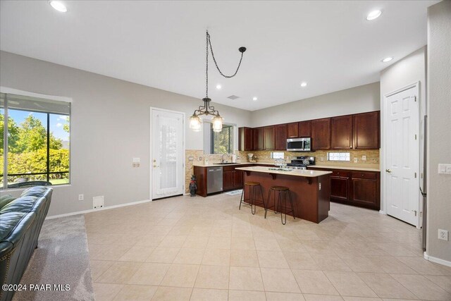 kitchen with a center island, stainless steel appliances, an inviting chandelier, a kitchen breakfast bar, and tasteful backsplash