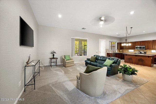 living room with ceiling fan with notable chandelier and light colored carpet