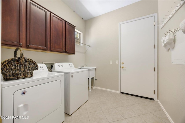 laundry room with washer and clothes dryer, cabinets, and light tile patterned floors