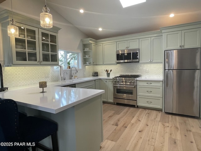 kitchen featuring a sink, vaulted ceiling, appliances with stainless steel finishes, a peninsula, and open shelves