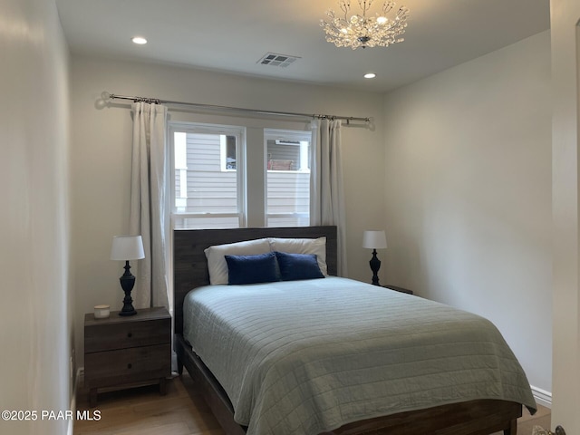 bedroom with an inviting chandelier, recessed lighting, wood finished floors, and visible vents