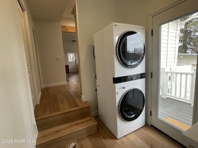 laundry area featuring stacked washer / drying machine, light wood-style floors, and laundry area