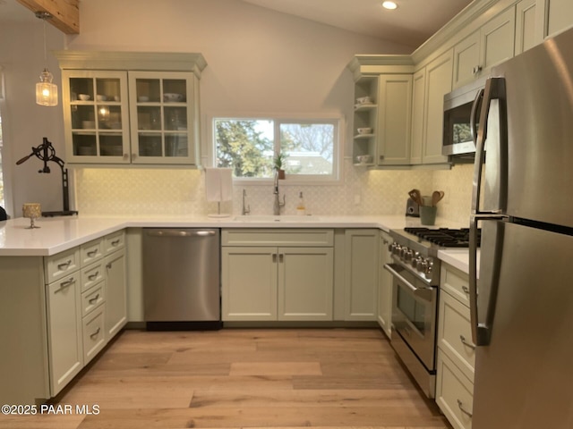 kitchen featuring a sink, stainless steel appliances, a peninsula, light countertops, and lofted ceiling