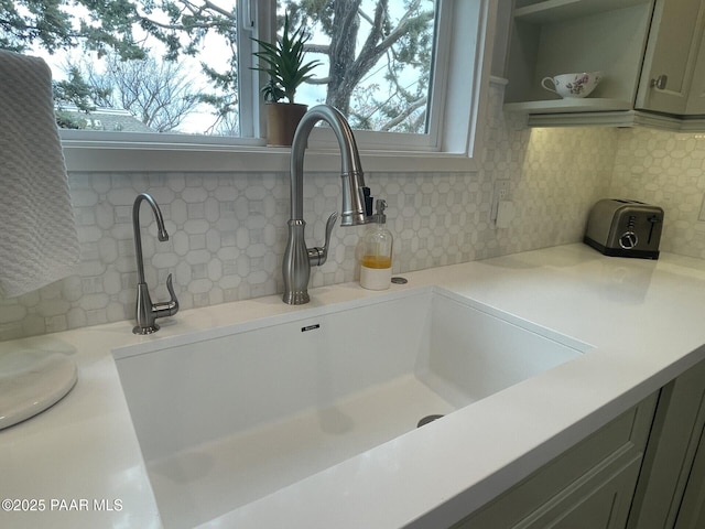 interior details with a sink, decorative backsplash, open shelves, and light countertops