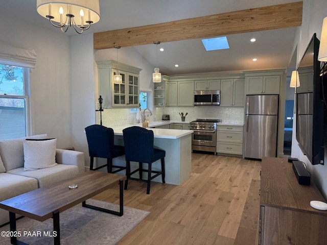 kitchen with light wood finished floors, a peninsula, stainless steel appliances, lofted ceiling with skylight, and tasteful backsplash