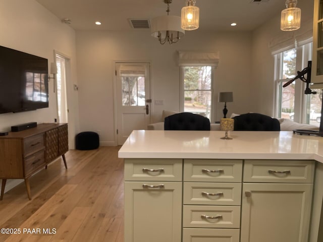 kitchen featuring hanging light fixtures, visible vents, light countertops, and light wood-style floors