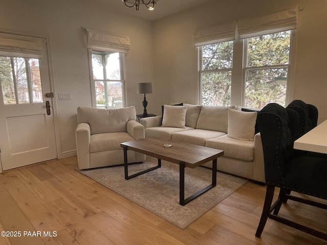 living room with light wood finished floors and an inviting chandelier