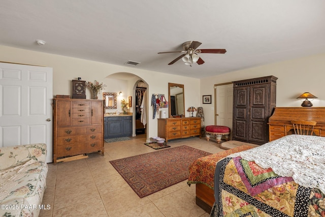 25820 N Poppy Dr, Paulden, AZ 86334 - bedroom with arched walkways, light tile patterned floors, ensuite bathroom, and a ceiling fan