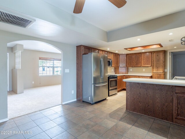 5700 N Concho Dr, Prescott Valley, AZ 86314 - kitchen with appliances with stainless steel finishes, arched walkways, light countertops, a ceiling fan, and light carpet