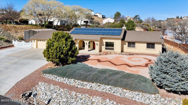 view of front of home featuring a residential view, concrete driveway, fence, and solar panels