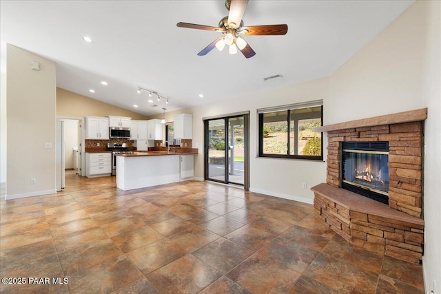 unfurnished living room with ceiling fan, a fireplace, baseboards, and vaulted ceiling