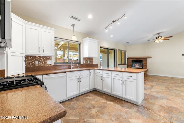 kitchen with visible vents, white cabinets, a sink, dishwasher, and a peninsula