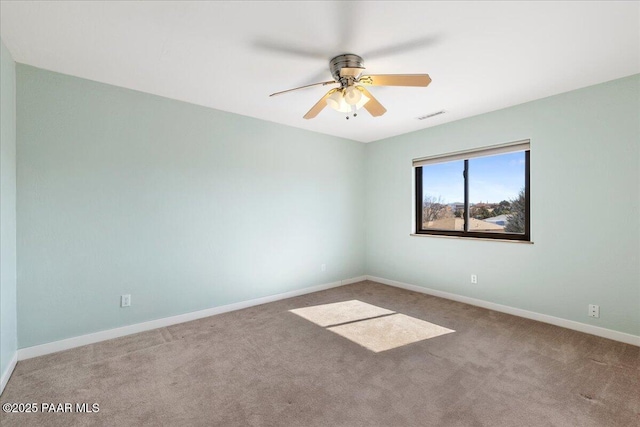 carpeted spare room with baseboards, visible vents, and ceiling fan