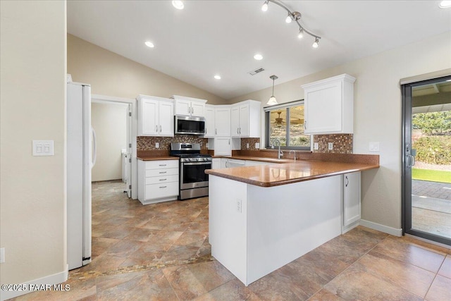 kitchen with stainless steel appliances, white cabinets, a peninsula, and decorative backsplash