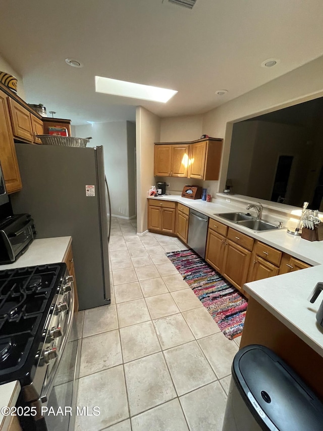 kitchen featuring appliances with stainless steel finishes, light tile patterned flooring, light countertops, and a sink
