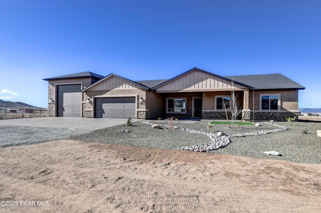 view of front of house with gravel driveway, an attached garage, covered porch, and stone siding