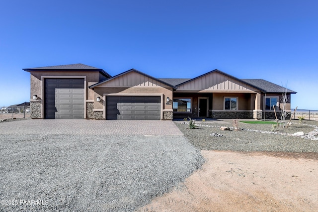 view of front of house with a garage, stone siding, driveway, and stucco siding