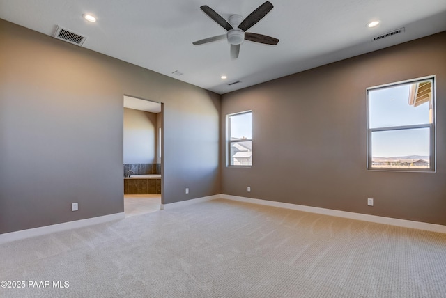 spare room with baseboards, light colored carpet, visible vents, and ceiling fan