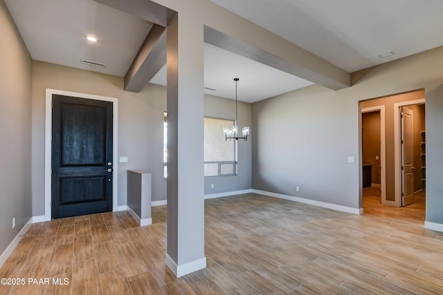 entrance foyer featuring visible vents, baseboards, light wood-style flooring, beamed ceiling, and a chandelier