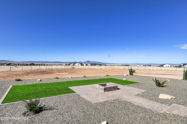 view of yard featuring a fenced backyard, a mountain view, an outdoor fire pit, and a patio