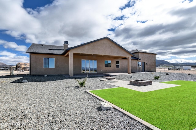 back of house with a patio area, stucco siding, and an outdoor fire pit