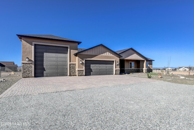 view of front of home with a garage, decorative driveway, fence, and stone siding