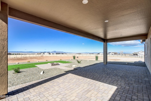 view of patio with fence, a mountain view, and an outdoor fire pit