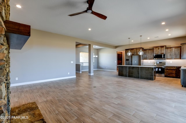 kitchen with open floor plan, appliances with stainless steel finishes, light countertops, and ceiling fan