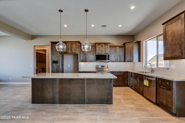 kitchen with wood finish floors, a kitchen island, recessed lighting, a sink, and appliances with stainless steel finishes