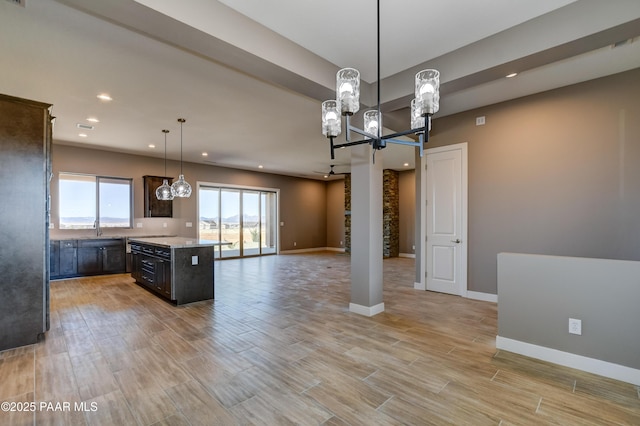 kitchen with baseboards, an inviting chandelier, light countertops, light wood-style floors, and open floor plan