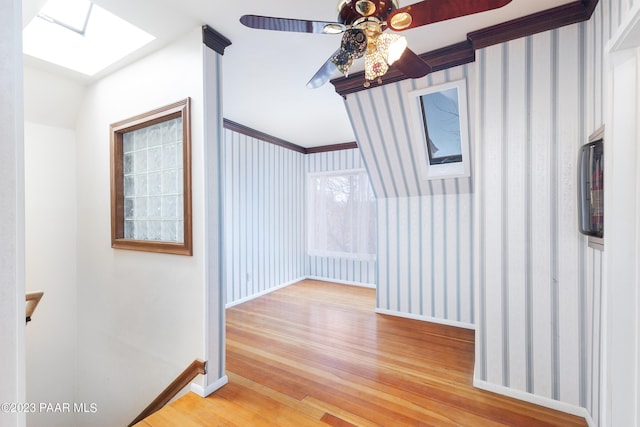 hall with hardwood / wood-style flooring, a skylight, and crown molding