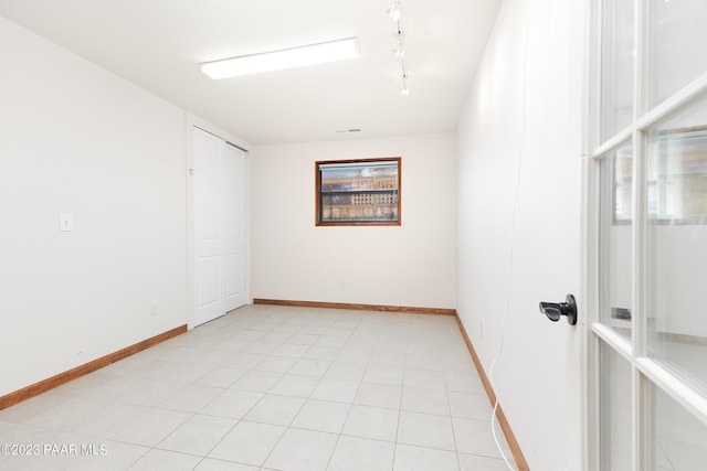 empty room with light tile patterned floors and track lighting