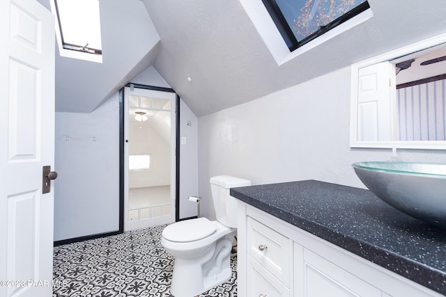 bathroom with vanity, toilet, and lofted ceiling with skylight