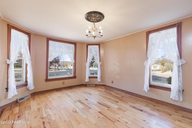 unfurnished dining area with a chandelier, light hardwood / wood-style flooring, and crown molding