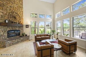 living room with tile patterned flooring, a towering ceiling, and a fireplace