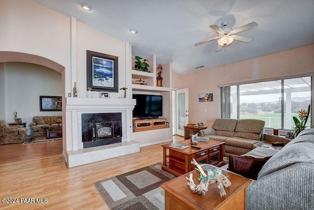 living room featuring ceiling fan, a fireplace, and light hardwood / wood-style flooring