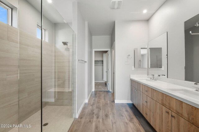 bathroom featuring hardwood / wood-style floors, vanity, plenty of natural light, and tiled shower