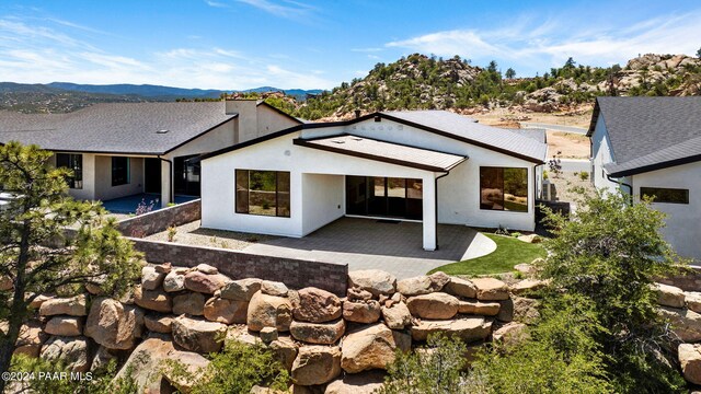 back of property featuring a mountain view and a patio