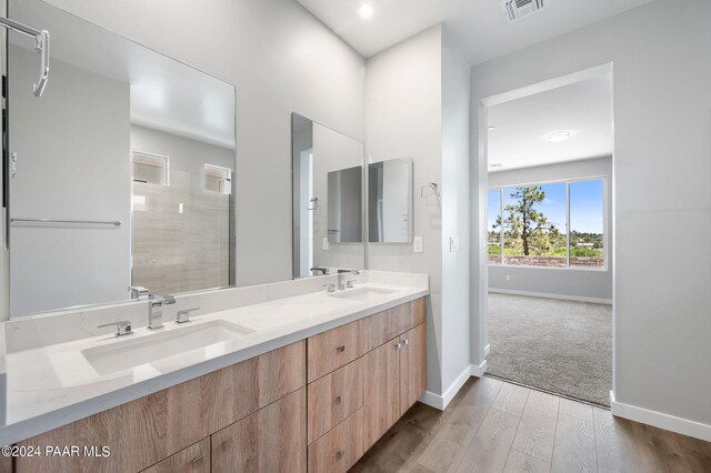 bathroom with hardwood / wood-style floors, vanity, and tiled shower