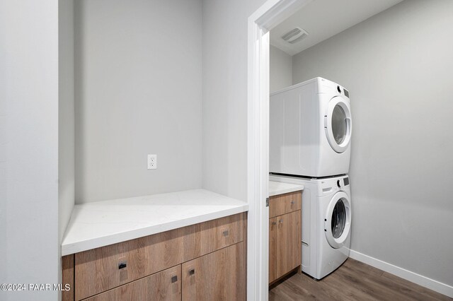 laundry room with cabinets, light hardwood / wood-style flooring, and stacked washer and clothes dryer